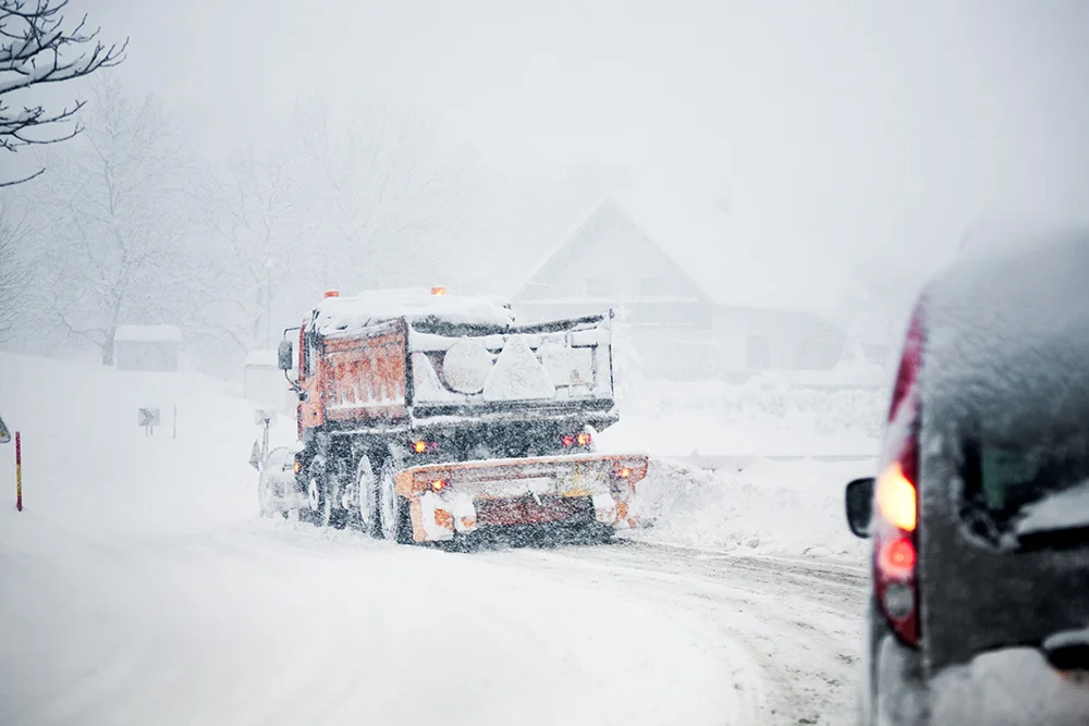 road with vehicles going through blizzard